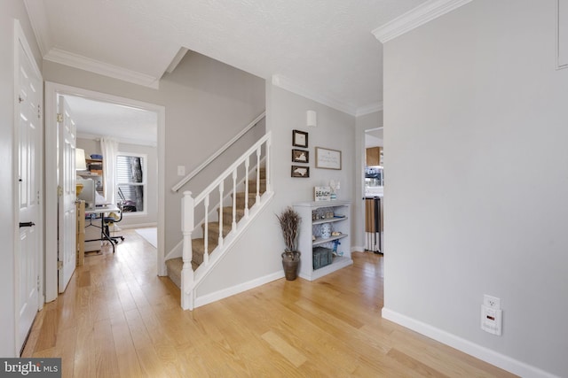 entrance foyer featuring stairway, baseboards, light wood-style floors, and ornamental molding