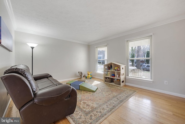 living area with baseboards, a textured ceiling, ornamental molding, and hardwood / wood-style flooring