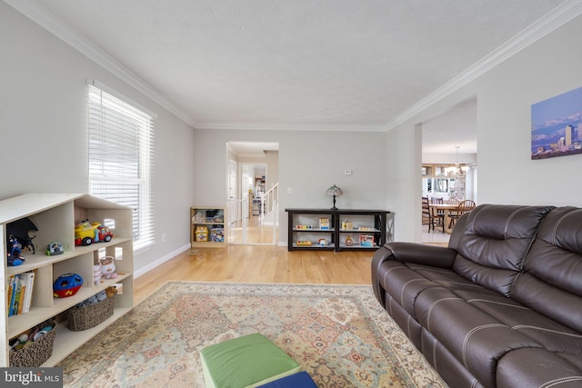 living area featuring ornamental molding, baseboards, an inviting chandelier, and wood finished floors