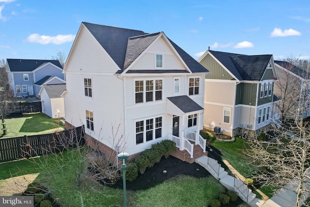 rear view of house with a shingled roof, central air condition unit, entry steps, a fenced backyard, and a yard