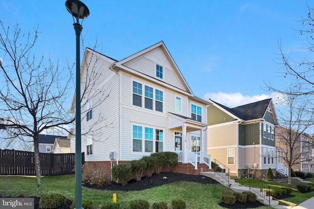 view of front of home featuring brick siding, a front lawn, and fence