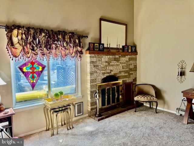 living area featuring a glass covered fireplace, baseboards, and carpet