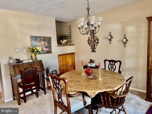 dining area featuring light carpet, baseboards, and an inviting chandelier