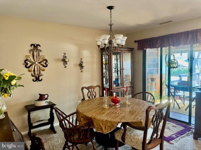 dining space featuring a chandelier, visible vents, baseboards, and carpet floors