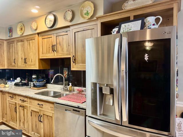 kitchen with a sink, light stone counters, recessed lighting, stainless steel appliances, and decorative backsplash