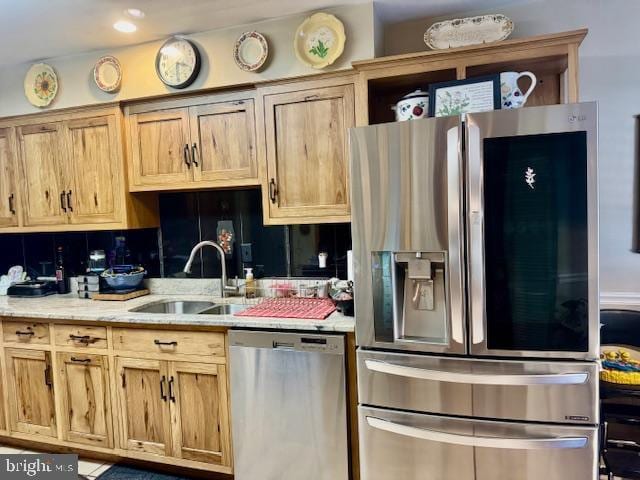 kitchen with light stone counters, backsplash, stainless steel appliances, and a sink