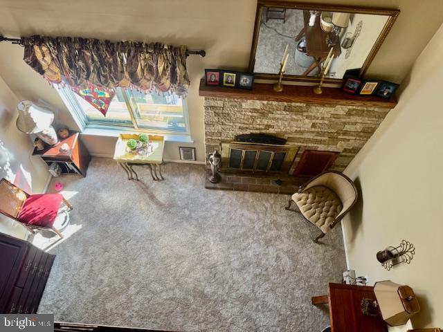 carpeted living area with a stone fireplace