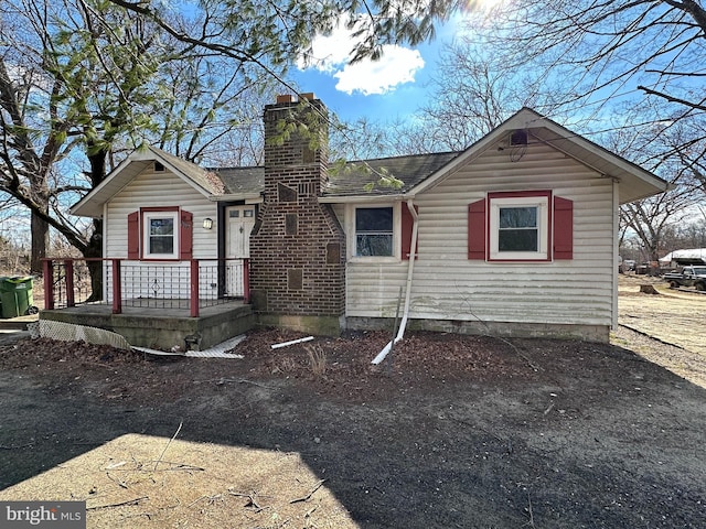 view of front facade featuring roof with shingles and a chimney