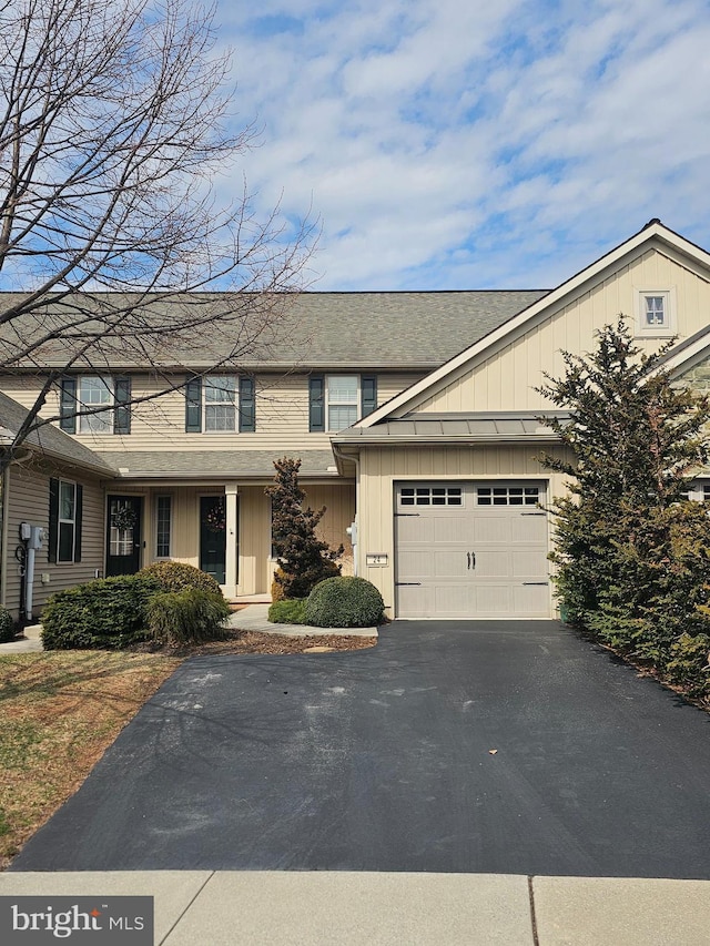 townhome / multi-family property with aphalt driveway, roof with shingles, board and batten siding, and an attached garage