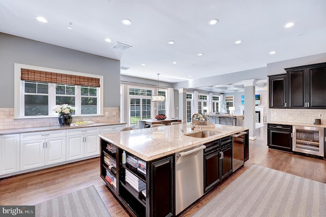6813 Millwood Rd, Bethesda, MD 20817 - kitchen featuring stainless steel dishwasher, wine cooler, a sink, a center island with sink, and white cabinetry