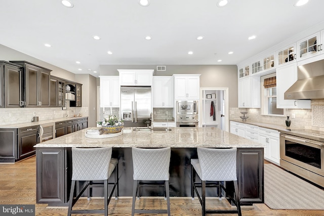 6813 Millwood Rd, Bethesda, MD 20817 - kitchen with built in appliances, wall chimney exhaust hood, backsplash, a spacious island, and recessed lighting