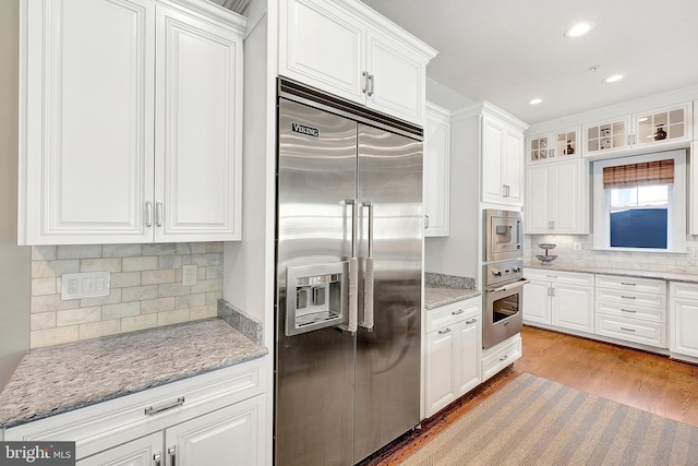 6813 Millwood Rd, Bethesda, MD 20817 - kitchen featuring built in appliances, white cabinets, decorative backsplash, light wood finished floors, and recessed lighting