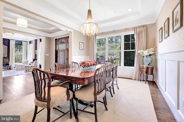 6813 Millwood Rd, Bethesda, MD 20817 - dining area featuring a tray ceiling, a decorative wall, crown molding, wood finished floors, and a chandelier