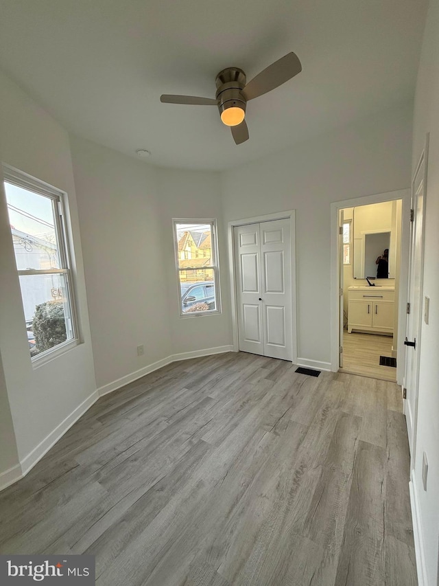 unfurnished bedroom with visible vents, ensuite bathroom, wood finished floors, a closet, and baseboards