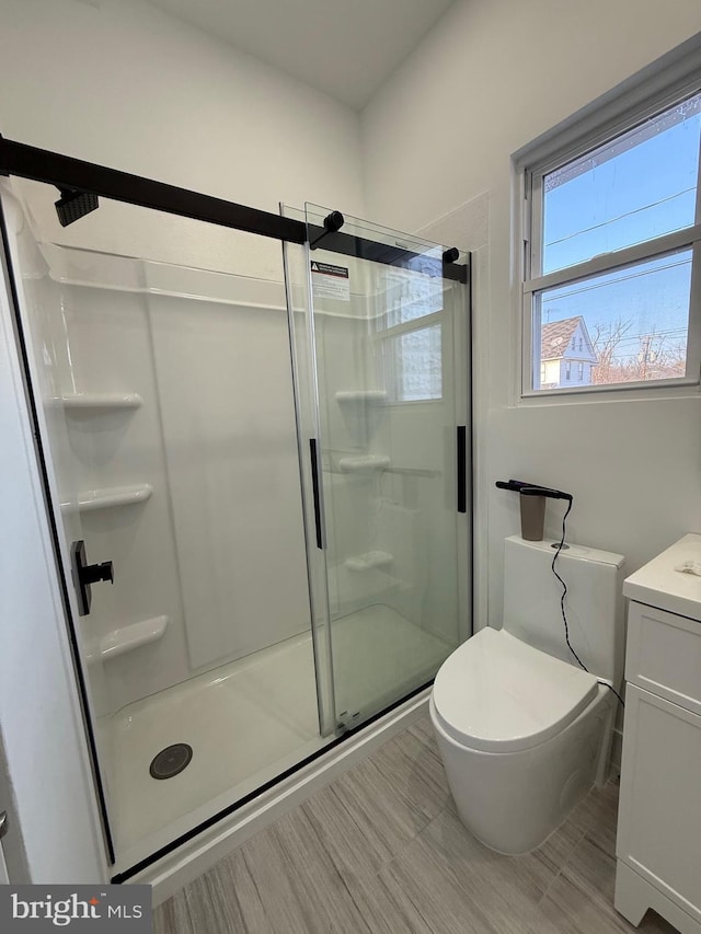 full bathroom with toilet, a stall shower, and vanity