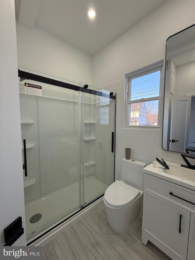 bathroom with recessed lighting, a stall shower, toilet, and vanity