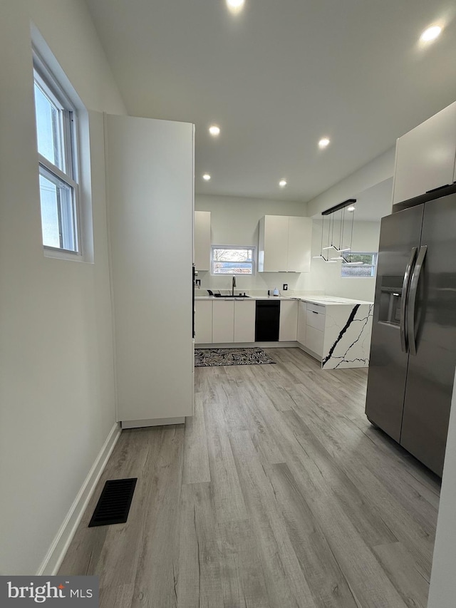 kitchen featuring visible vents, light wood-style flooring, stainless steel refrigerator with ice dispenser, white cabinetry, and dishwasher