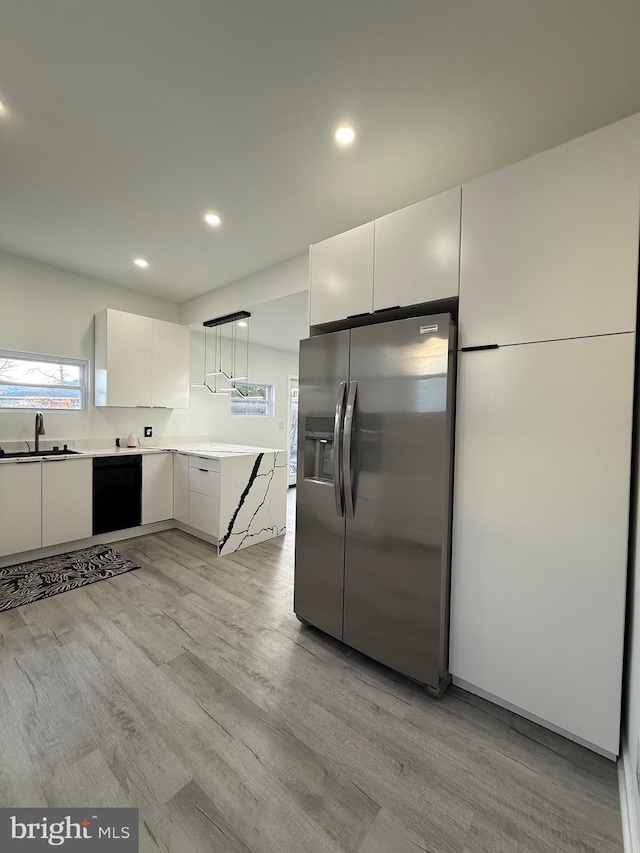 kitchen featuring black dishwasher, stainless steel fridge with ice dispenser, light wood finished floors, and a sink