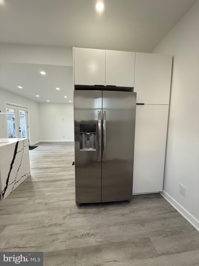 kitchen featuring stainless steel fridge with ice dispenser, recessed lighting, french doors, light wood-style flooring, and white cabinets