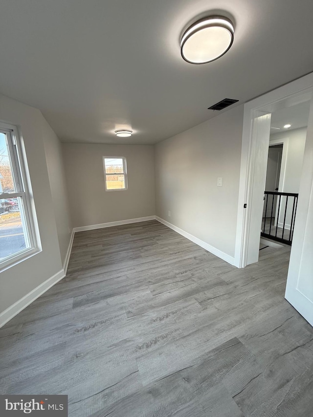 unfurnished room with visible vents, plenty of natural light, and wood finished floors