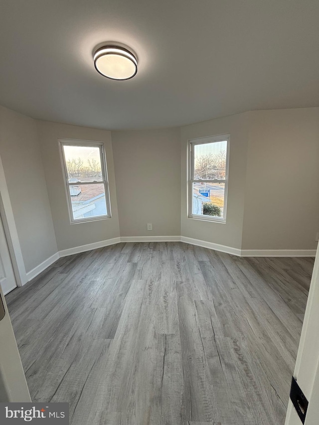 unfurnished room with a wealth of natural light, baseboards, and wood finished floors