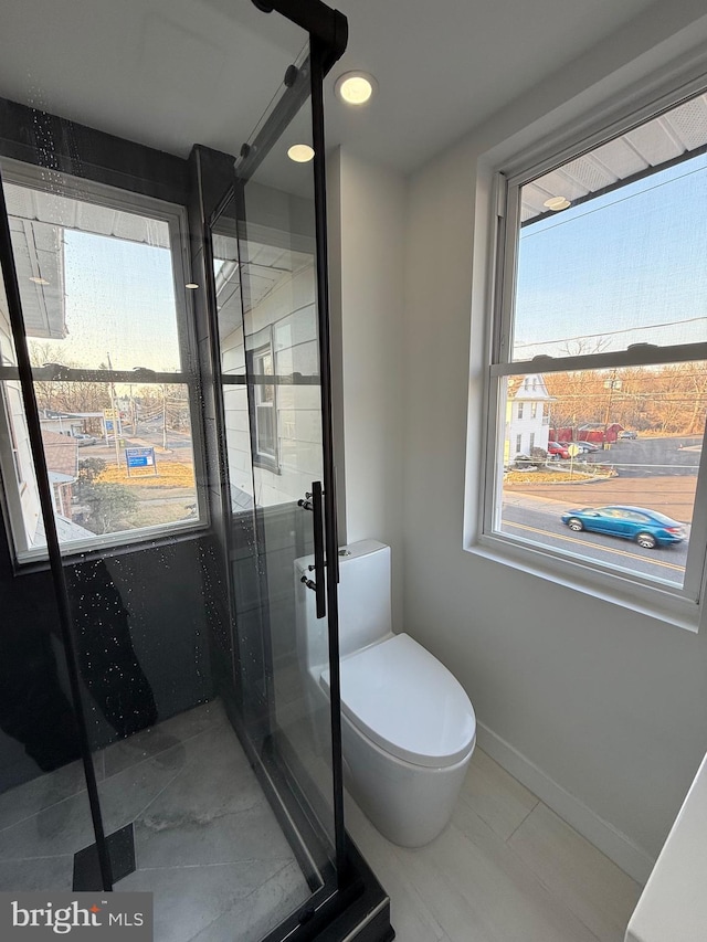 bathroom with toilet, baseboards, and a stall shower