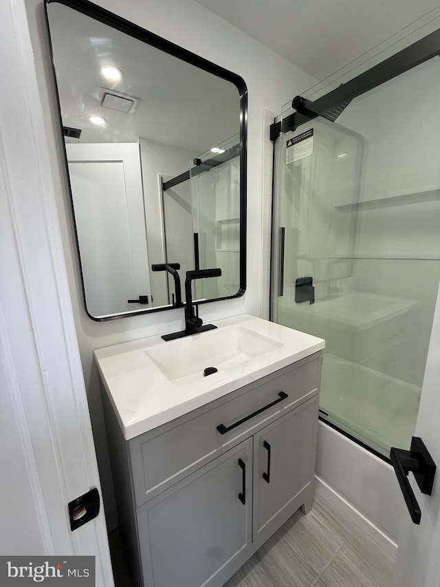 bathroom featuring visible vents, bath / shower combo with glass door, and vanity