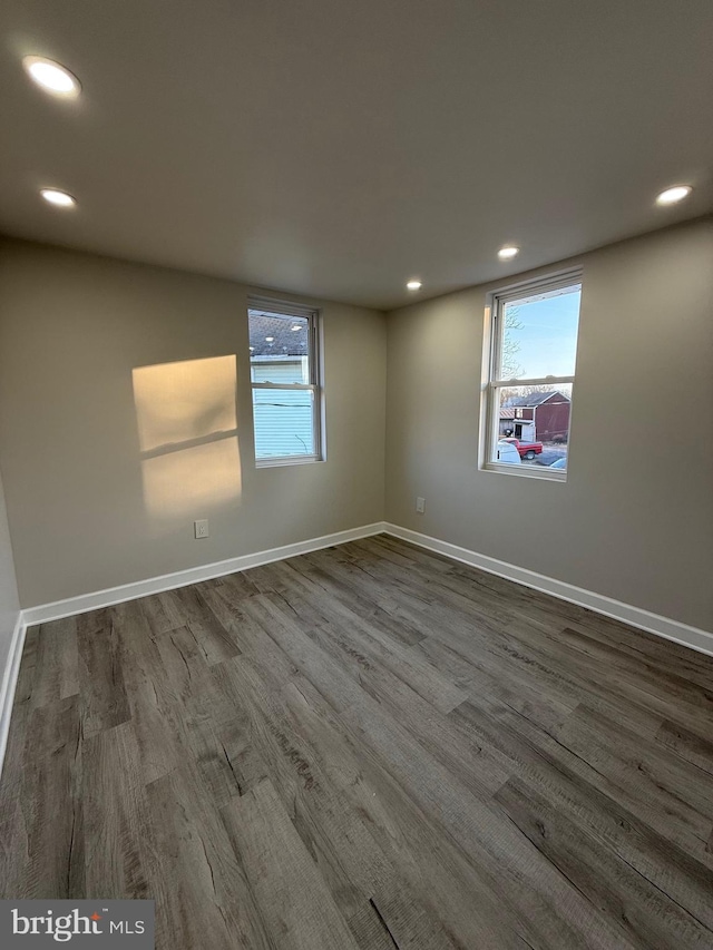 spare room with baseboards, a healthy amount of sunlight, and wood finished floors