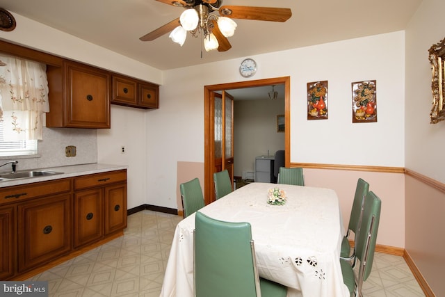 dining room with baseboards, light floors, and a ceiling fan