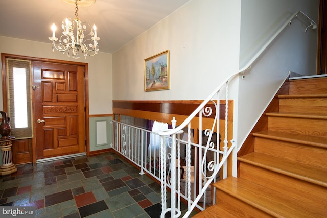 foyer with a chandelier, stone finish floor, and stairs