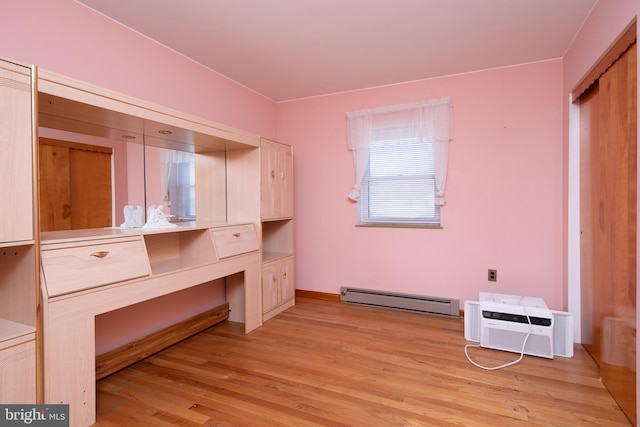 unfurnished office with a baseboard heating unit, light wood-style floors, and a wall mounted AC