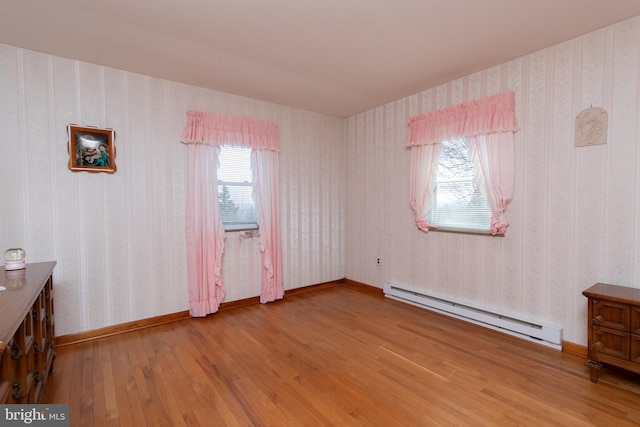 empty room featuring hardwood / wood-style floors, wallpapered walls, and a baseboard radiator