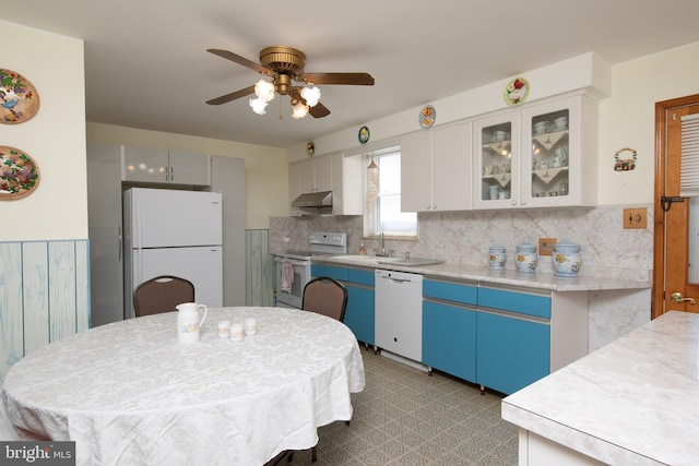 kitchen with under cabinet range hood, glass insert cabinets, white appliances, and light countertops