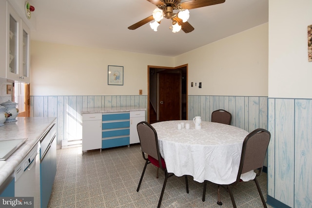 dining space with tile patterned floors, a wainscoted wall, and ceiling fan