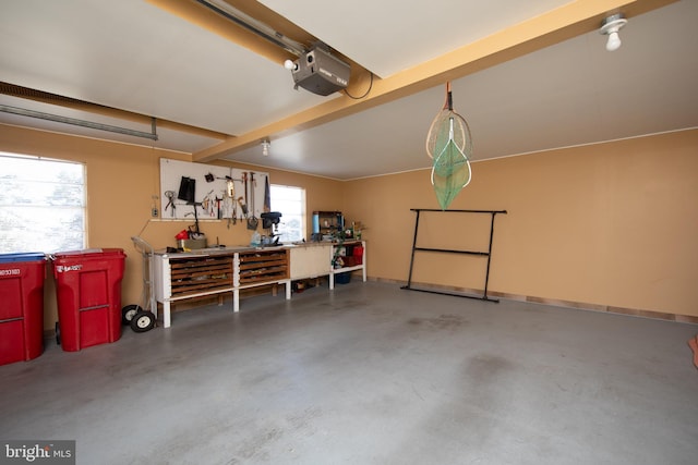 garage with a workshop area, a garage door opener, and baseboards