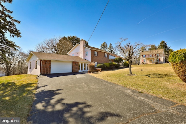 view of front of property featuring a chimney, french doors, a garage, aphalt driveway, and brick siding