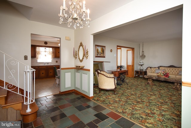 foyer entrance featuring an inviting chandelier, stairway, a fireplace, and stone tile floors