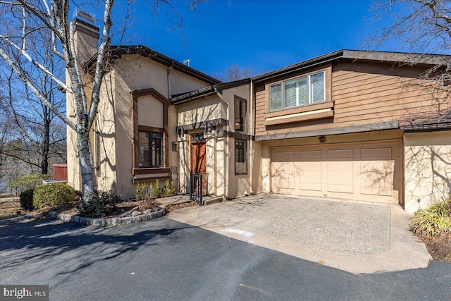 view of front of house with stucco siding, an attached garage, and driveway