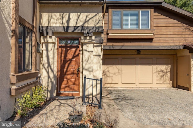 property entrance featuring a garage, driveway, and stucco siding