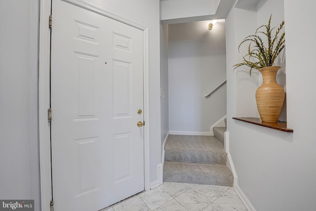 foyer with stairway, baseboards, and marble finish floor