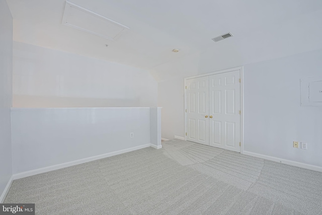 carpeted spare room with visible vents, attic access, and baseboards