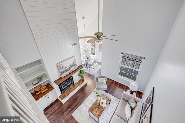 living room featuring visible vents, ceiling fan with notable chandelier, a high ceiling, and wood finished floors