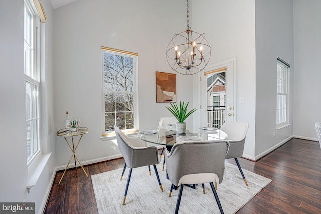 dining space featuring a healthy amount of sunlight, a towering ceiling, and wood finished floors