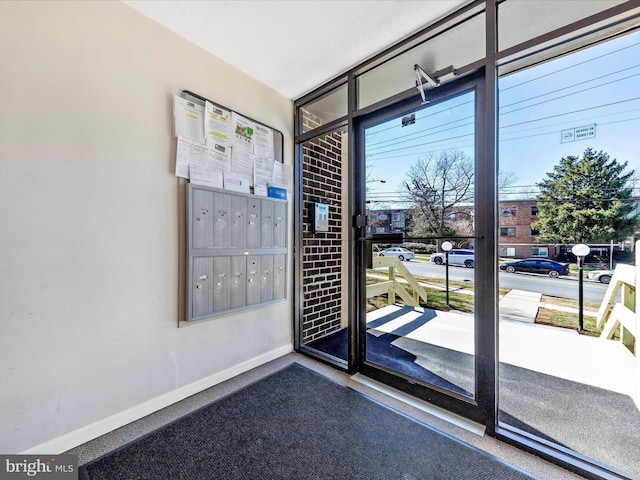 entryway with a wall of windows, mail area, and baseboards