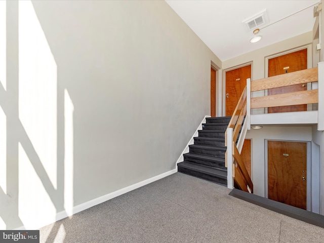 stairway with visible vents, baseboards, and carpet