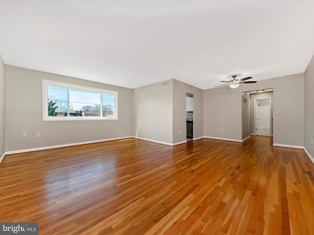 unfurnished living room featuring light wood finished floors, visible vents, ceiling fan, and baseboards