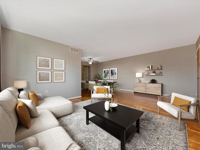 living room featuring baseboards, wood finished floors, visible vents, and ceiling fan