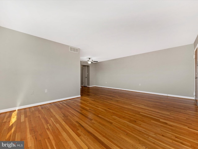 unfurnished room with visible vents, ceiling fan, baseboards, and hardwood / wood-style floors