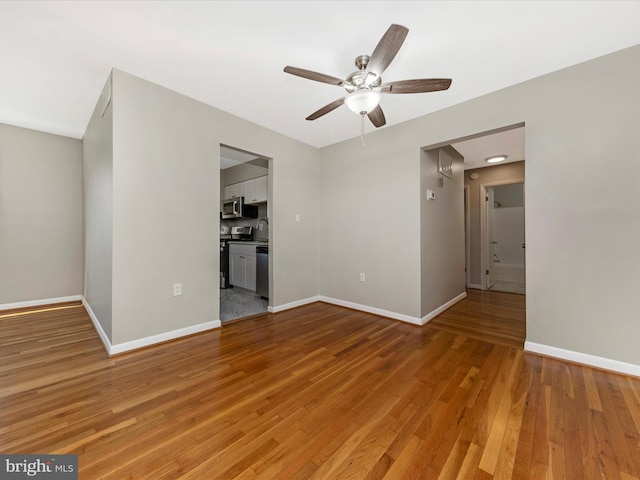 unfurnished living room featuring a sink, baseboards, light wood-type flooring, and ceiling fan