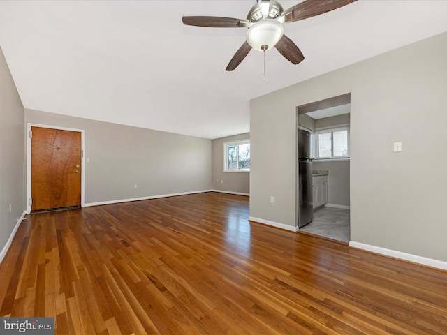 unfurnished living room with ceiling fan, baseboards, and wood finished floors